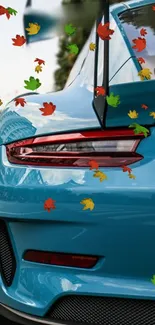 Blue sports car with colorful autumn leaves floating around.