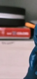 A blue dinosaur figurine on a desk with blurred background.