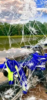 Blue dirt bike parked by a scenic lake with vibrant colors.