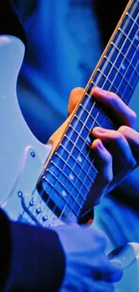 Close-up of hands playing a blue electric guitar.