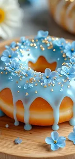 Donut with blue frosting and flowers on wooden plate.