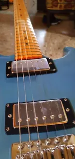 Close-up of blue electric guitar with focus on strings and pickups.