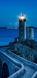 Lighthouse illuminating night sky by the ocean.