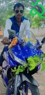 Man on a blue motorcycle surrounded by greenery.