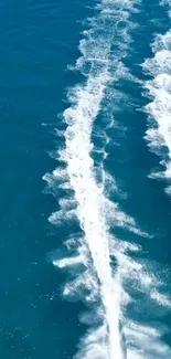 Aerial view of white trails over deep blue ocean waves.