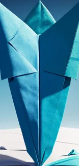 Blue origami flower against sky background, artistic design.