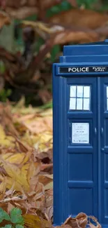 Blue police box amidst autumn leaves background.