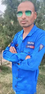 Person in a vibrant blue shirt with outdoor greenery background.