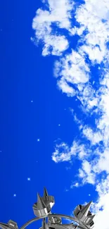 Vibrant blue sky with clouds and a metallic structure on mobile wallpaper.