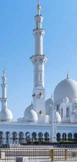 Elegant mosque under clear sky with domes and minarets.