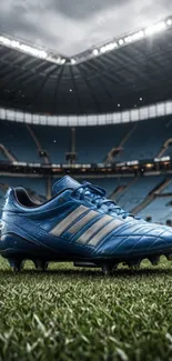 Blue soccer cleat on green field with stadium backdrop.