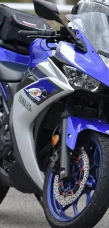 Blue sport motorcycle stands parked on pavement in an urban setting.