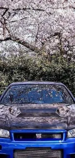 Blue sports car under cherry blossoms, blending nature and technology.