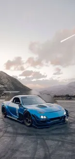 Blue sports car drifting with mountain backdrop at dusk.