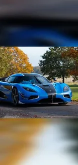 A sleek blue sports car on an autumn road with colorful trees.