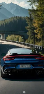 Blue sports car driving on a forest road with mountains in the background.