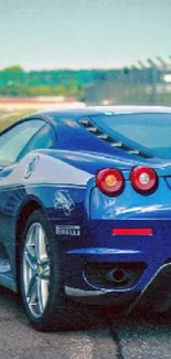 Blue sports car on a race track with vibrant sky background.