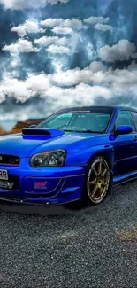 Blue sports car with cloudy sky and gold wheels on a roadway.