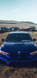 Blue sports car parked in a field with a clear sky.