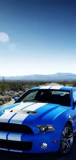 Blue sports car on desert road under blue sky.