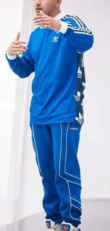 Person in a stylish blue tracksuit with fashion elements on a clean background.