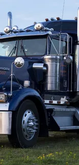 Dark blue classic semi-truck on grassy field.