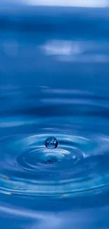 Blue water droplet creating ripples in a serene, calming scene.