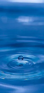 Serene blue water droplet creating ripples in a tranquil setting.