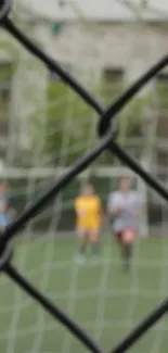 Blurred view of a soccer field through a fence, creating an artistic effect.