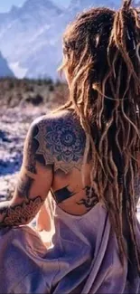 Bohemian woman with dreadlocks in snowy mountain landscape.