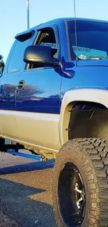 Vibrant blue pickup truck with large tires and rugged design on road.