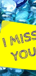 Yellow 'I Miss You' note on blue gems background wallpaper.