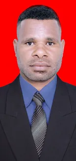 Man in a dark suit with a red background wallpaper.