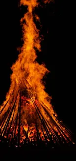 Vibrant bonfire with tall flames against night sky.