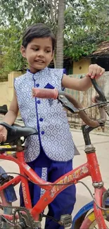 Smiling child with bicycle in garden setting.