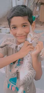 Boy smiling and holding cute cat outdoors.