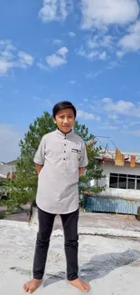 Boy standing on rooftop under blue sky