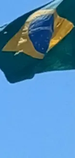 Brazilian flag waving against bright blue sky.