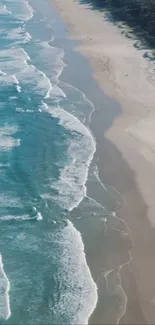 Aerial view of ocean waves meeting sandy beach on a sunny day.