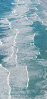 Aerial view of ocean waves crashing on a sandy beach, creating a soothing pattern.