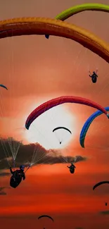 Paragliders soaring against a vibrant orange sunset sky.