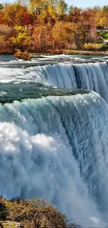 Dynamic waterfall against autumn landscape and misty blue sky.