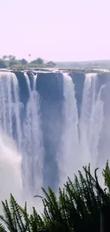 Majestic waterfall flowing into lush greenery background.