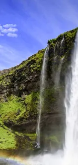 Stunning waterfall with lush green landscape and vivid blue sky.