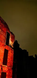 Illuminated brick wall against a dark night sky with urban landscape ambiance.