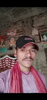 Man in rustic room with brick wall and colorful decor.