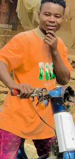 Man posing on motorcycle in bright orange shirt.