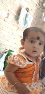 Father holding a smiling baby in an orange outfit, in a bright home setting.