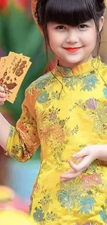 Child in vibrant traditional yellow attire holding envelopes.