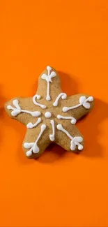 Star-shaped gingerbread cookie with icing on an orange background.